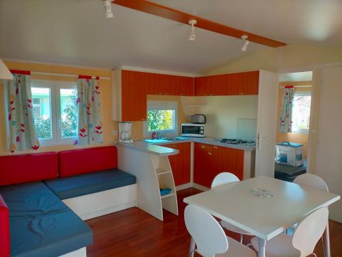 - une petite cuisine avec des placards rouges et une table blanche dans l'établissement Gîte à bâbord, à Cabariot