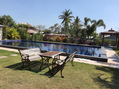 a picnic table and bench next to a swimming pool at Nadee resort in Udon Thani