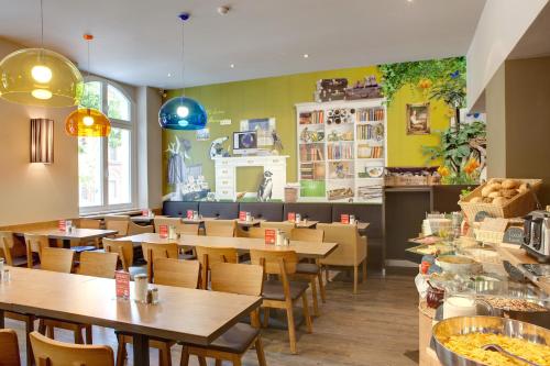 a restaurant with wooden tables and chairs and yellow walls at MEININGER Hotel Berlin Mitte in Berlin