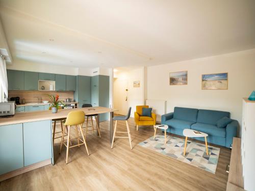 - une cuisine et un salon avec un canapé bleu et des chaises dans l'établissement appartement du Bellay, à Sarlat-la-Canéda
