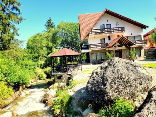 a house next to a river with a large rock at VILA VIBRANT in Bran