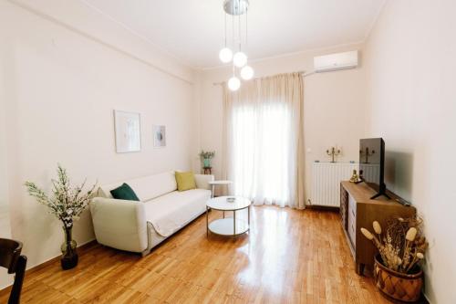Una sala de estar con un sofá blanco y un televisor. en El.Venizelos Quiet Lux apt. (Aristotelous sqr), en Tesalónica