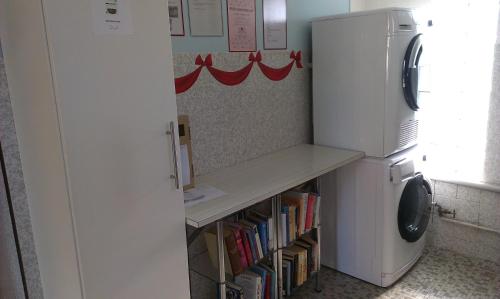 a kitchen with a refrigerator and a shelf with books at Camping Schönengrund in Schönengrund