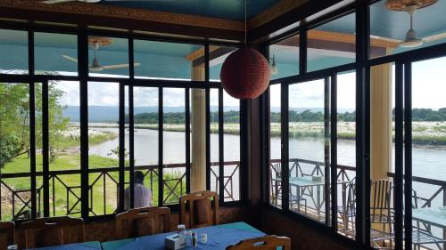 a dining room with a view of the river at Jungle Wildlife Camp in Sauraha