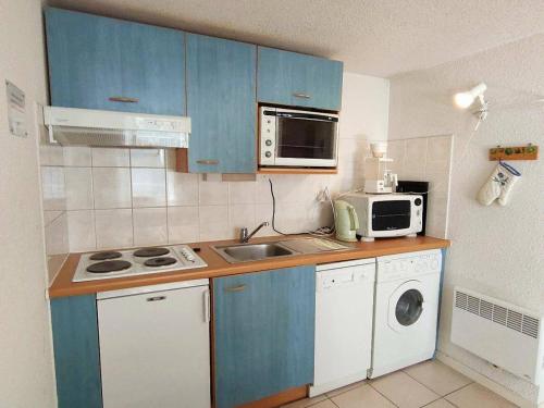 Elle comprend une petite cuisine avec des placards bleus et un four micro-ondes. dans l'établissement Appartement Centre-Ville 6-8 Pers, 2 Sdb, Balcon, Proche Activités Hivernales - FR-1-234-78, à Cauterets