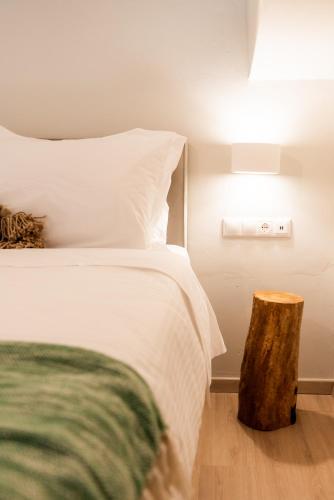 a bedroom with a bed with a wooden stump next to it at Guru accommodations in Mýkonos City