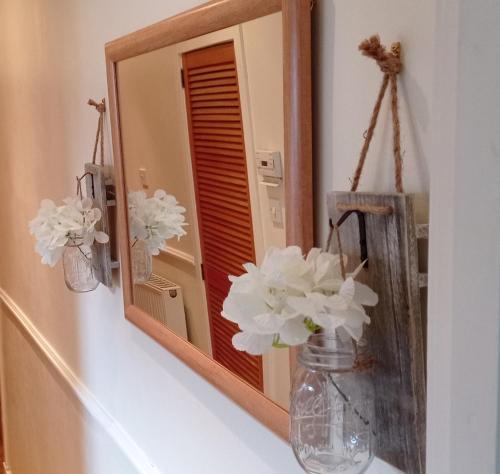 a mirror on a wall with flowers in a vase at Isla Way Stays in Keith