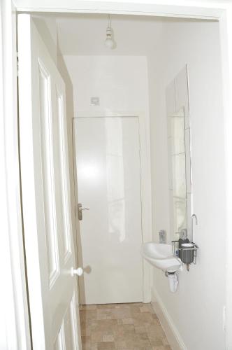 a white bathroom with a sink and a mirror at Virtue House in Woolwich