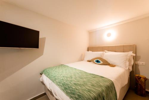 a bedroom with a bed with a flat screen tv on the wall at Guru accommodations in Mýkonos City