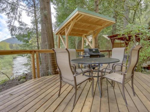 a patio with a table and chairs on a deck at River View Cabin - Meredith Lodging in Welches