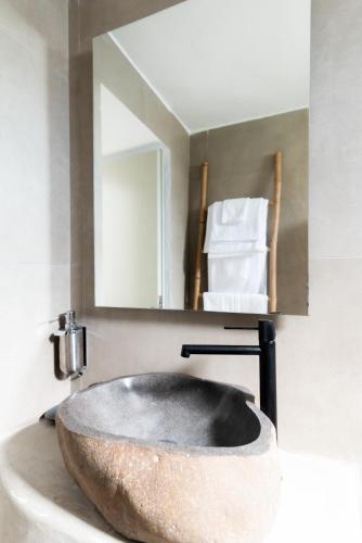 a stone sink in a bathroom with a mirror at Guru accommodations in Mýkonos City