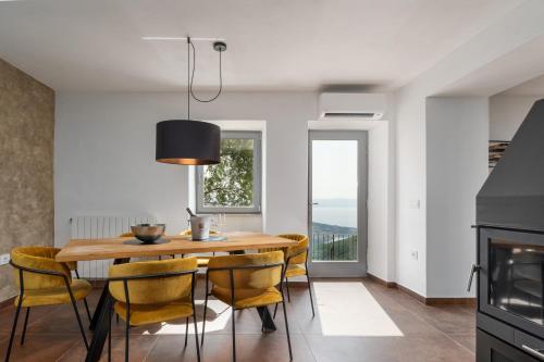 uma sala de jantar com uma mesa de madeira e cadeiras amarelas em CASA GIUSEPPE Luxury house with an amazing view em Labin