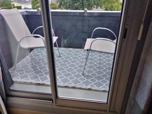 a glass door with two chairs on a balcony at Chez Bernard et Nicole in Betton