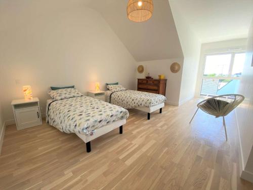 - une chambre avec 2 lits et une chaise dans l'établissement Duplex lumineux à Bénodet: plage et thalasso à pied, terrasse, parking et abri vélo inclus - FR-1-481-117, à Bénodet