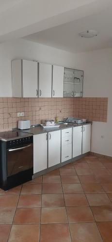 kuchnia z białymi szafkami i czarnym piecem w obiekcie Villa Dobra Family Apartments w mieście Vir