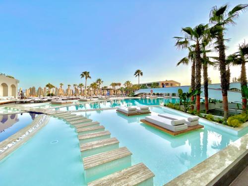 een afbeelding van een zwembad van het resort met palmbomen bij LAUR HOTELS Experience & Elegance in Didim