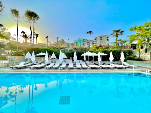 a swimming pool with lounge chairs and umbrellas at LAUR HOTELS Experience & Elegance in Didim