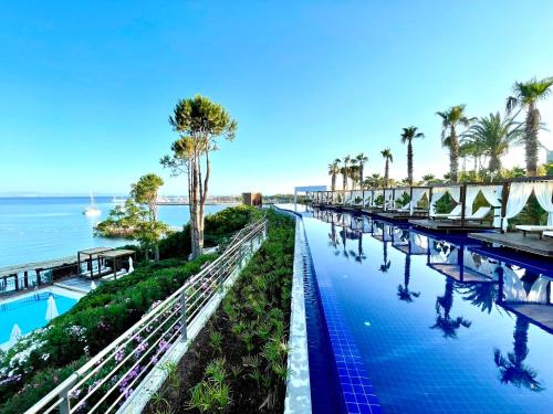 a swimming pool with palm trees and the ocean at LAUR HOTELS Experience & Elegance in Didim