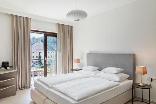 a white bedroom with a large bed and a window at Hotel Linde in Maria Wörth