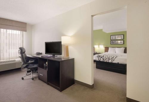 a hotel room with a desk with a computer and a bed at Sleep Inn Tanglewood in Roanoke