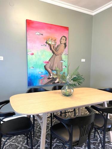 a table with chairs and a painting on the wall at APTER-Boutique Apartment אפטר - דירת בוטיק בכנרת in Tiberias