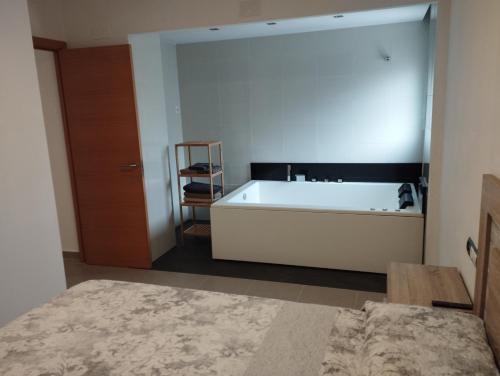 a bathroom with a tub and a table and a chair at Atico con hidromasaje, terraza y piscina en EbreHogar in Amposta