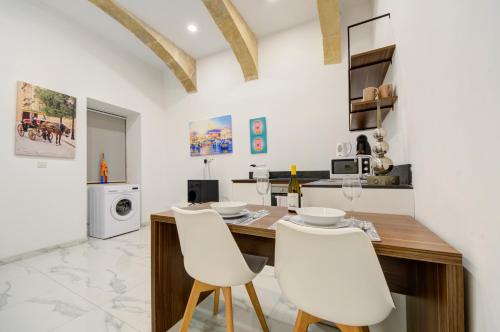 a kitchen with a wooden table and white chairs at Tritoni Harbour suites - Valletta in Valletta