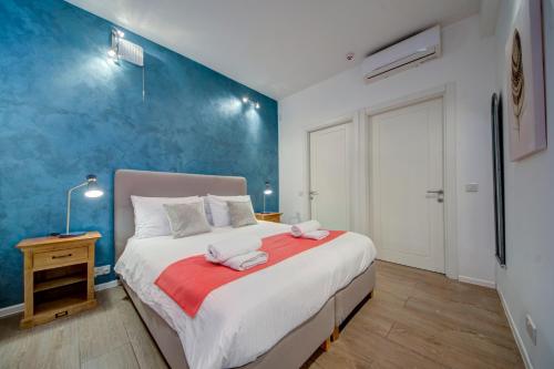 a bedroom with a large bed and a blue wall at Tritoni Harbour suites - Valletta in Valletta