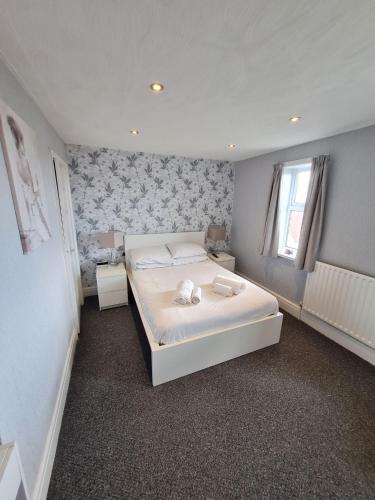 a bedroom with a large white bed and a window at Queens Plaza Hotel in Blackpool