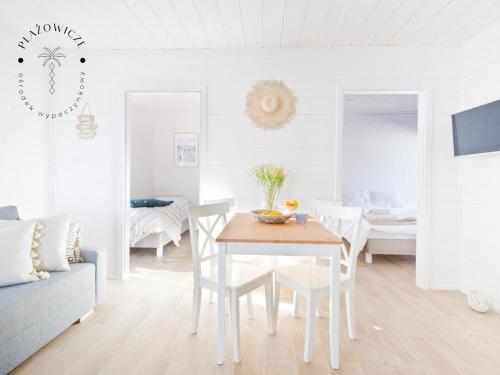ein weißes Wohnzimmer mit einem Tisch und Stühlen in der Unterkunft PLAŻOWICZE - domki letniskowe w Mielnie in Mielno