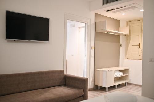 a living room with a couch and a tv on the wall at Hotel Baia Delle Sirene in Taormina