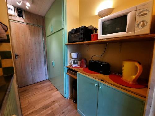 une cuisine avec un four micro-ondes au-dessus d'un comptoir dans l'établissement Studio pour 2 personnes avec balcon Sud face au jardin ESF, proche des pistes et remontées mécaniques - FR-1-452-269, aux Menuires