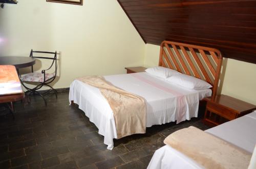 a bedroom with a bed and a desk and a table at Pousada Chalés da Estalagem in São Bento do Sapucaí