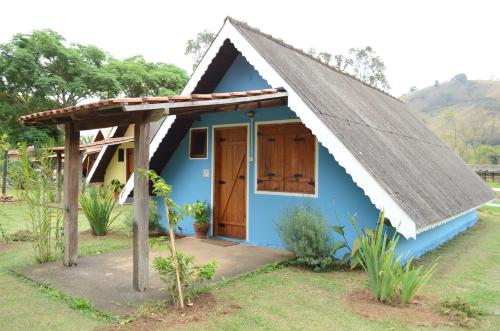a small blue house with a thatched roof at Pousada Chalés da Estalagem in São Bento do Sapucaí