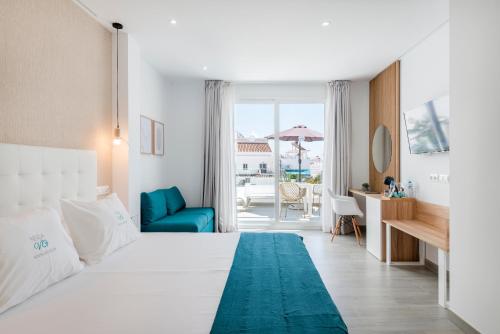 um quarto de hotel com uma cama branca e uma cadeira azul em Nerja VG Hostal Boutique em Nerja