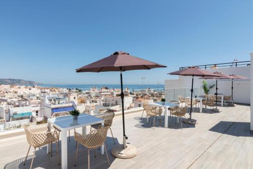 a patio with tables and umbrellas on a roof at Nerja VG Hostal Boutique in Nerja