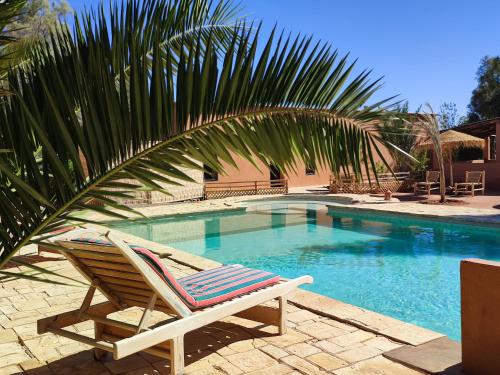 a lounge chair sitting next to a swimming pool at Maison d'hôtes Tigminou - Adults Only in Aït Ben Haddou