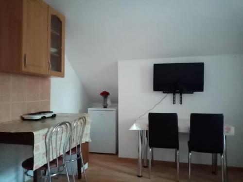a kitchen with a table with chairs and a tv on the wall at Apartmán Pohoda in Teplý Vrch