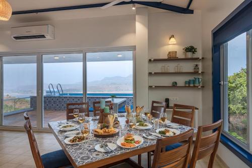 a dining room with a table with food on it at SaffronStays Kaia Waters by Kosha Villas, Pawna - Greek style villa with panoramic view of Pawna lake in Kolvan