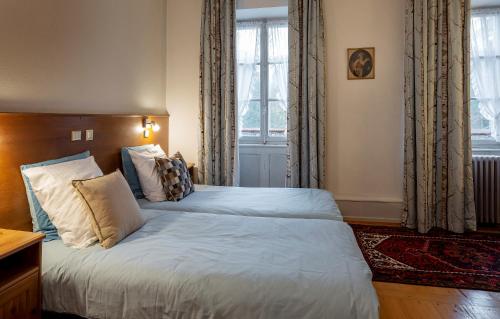 a bedroom with a bed with white sheets and a window at Hôtel-Résidence La Rubanerie in Schirmeck