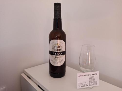 een fles bier op een tafel naast een glas bij Apartamento Nayca in Jerez de la Frontera