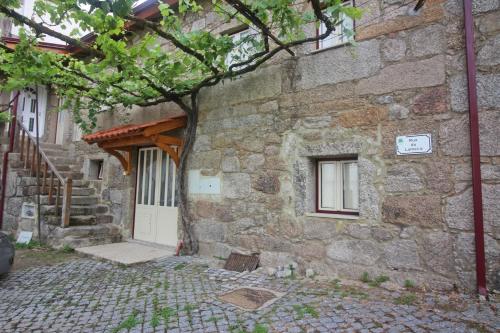 a stone building with a white door and a tree at Casa da Lameira I by Gerês Casas in Geres