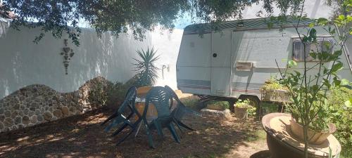 an rv parked next to a house with chairs and plants at Mi Cachito in Los Caños de Meca