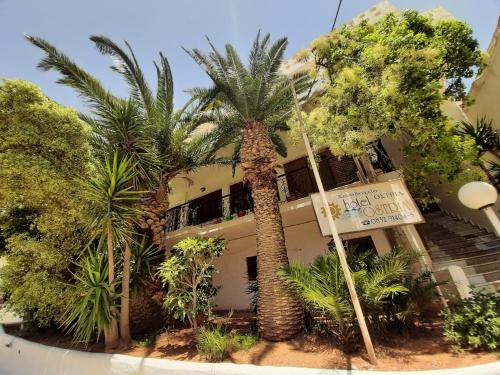 a building with palm trees and a sign in front of it at Ostria in Agia Galini