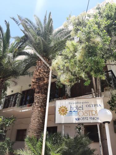 a palm tree in front of a building with a sign at Ostria in Agia Galini