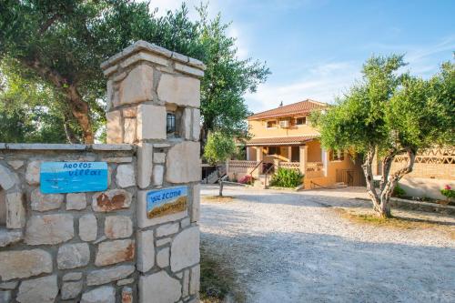 eine Steinmauer mit einem Schild vor einem Haus in der Unterkunft Aeolos Zante Villas with Heated Pool in Vasilikos