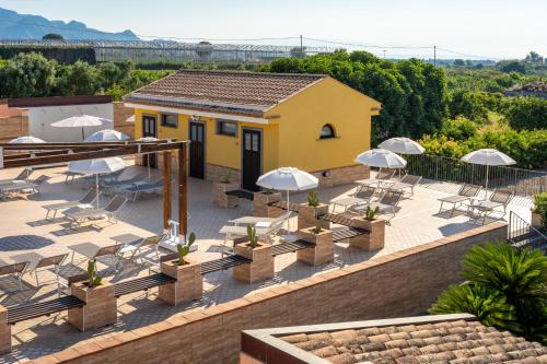 a patio with white chairs and tables and a building at La Terra Dei Sogni Country Hotel in Fiumefreddo di Sicilia