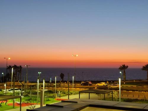 a parking lot with benches and lights in front of the ocean at Vert Lagoon Netanya By AFI Hotels in Netanya