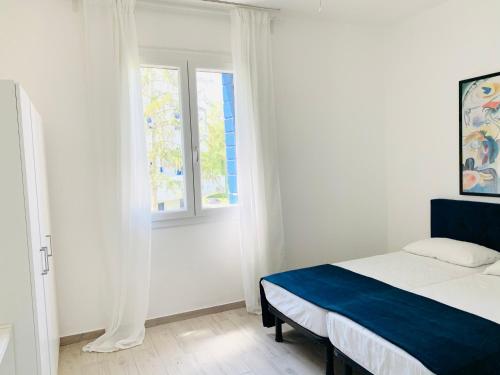 a white bedroom with a bed and a window at Villa Malta in Duna Verde