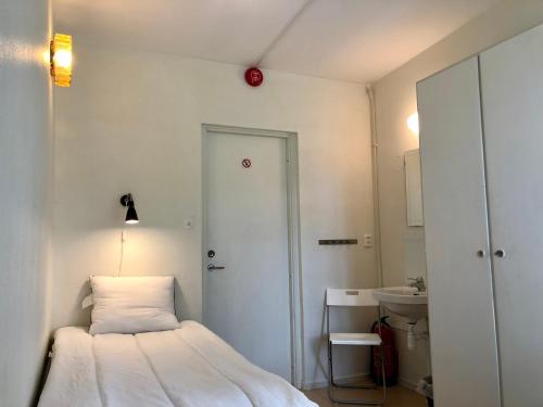 a small bedroom with a bed and a sink at Vandrarhem, Hostel in Hällestrand Semesterby in Strömstad